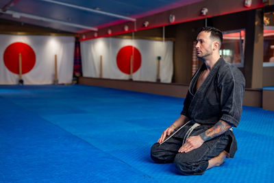 Portrait of karate man in focus position with japan flag on the wall