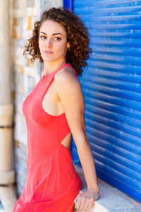 Portrait of young woman standing against wall