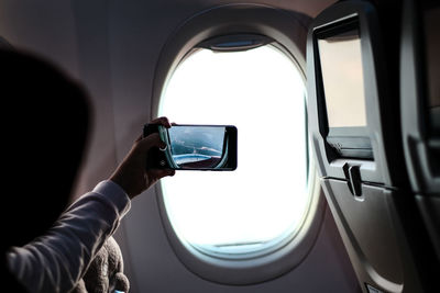 Midsection of man using mobile phone in airplane