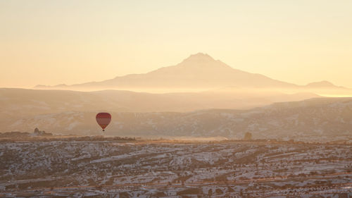 Hot air balloon flying over mountains against sky