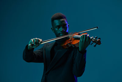 Man playing violin against clear blue sky