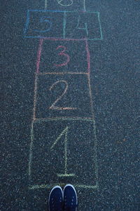 Low section of person standing hopscotch on footpath