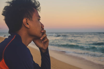 Portrait of mid adult man at beach against sky during sunset