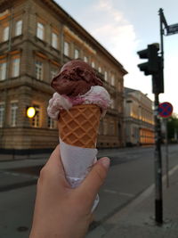 Midsection of person holding ice cream cone in city