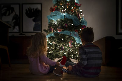 Siblings holding their elf while watching the christmas tree