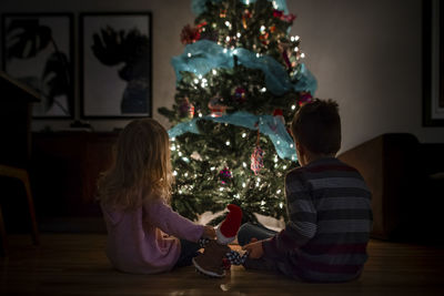 Siblings holding their elf while watching the christmas tree