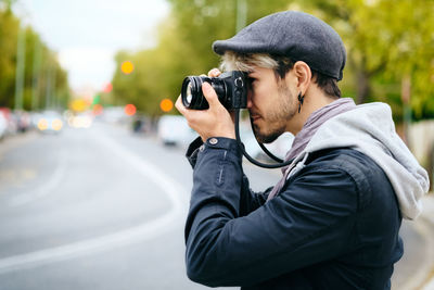 Side view of man photographing with camera in city