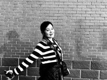 Portrait of smiling woman walking by brick walls