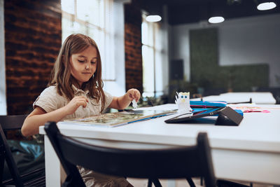 Young woman using mobile phone while sitting on table