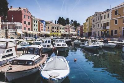 Boats moored in canal amidst buildings in city