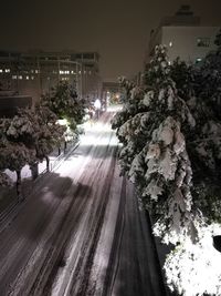 Road by illuminated city against sky at night