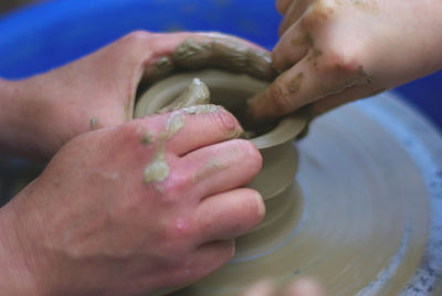 Cropped hands of people making clay pot