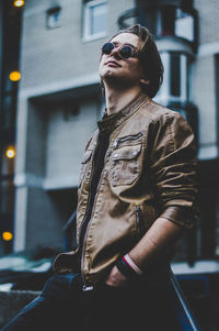 Close-up of man wearing sunglasses standing in city at night