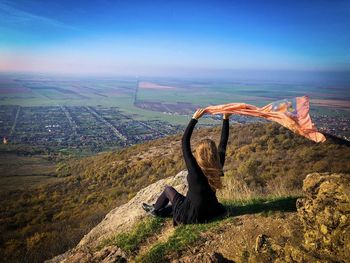 Woman on top of the mountain holding a scarf floating in the wind