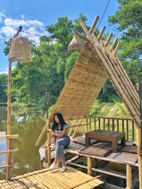 Woman sitting on wooden structure against sky