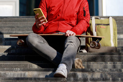 Midsection of man using mobile phone while sitting on steps