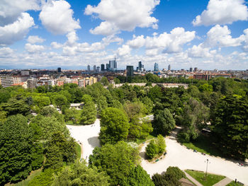 Trees and buildings against cloudy sky