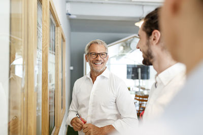 Smiling businessman looking at colleagues in office