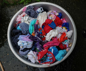 Colorful baby clothes for washing in an aluminum basin.