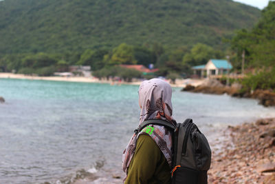 Rear view of woman standing at beach