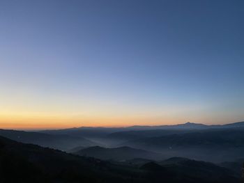 Scenic view of mountains against clear sky during dawn 