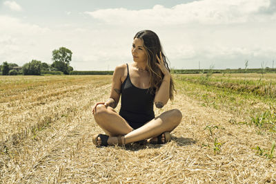 Beautiful tattooed girl with black swimsuit sitting on the grass 