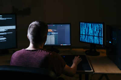 Hacker using computer while sitting in dark office