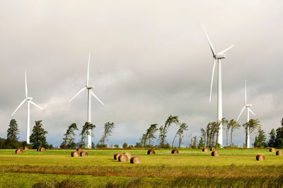 Windmill on field against cloudy sky