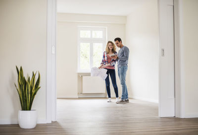 Young couple in new home with tablet and ground plan