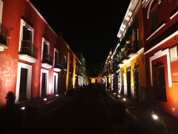 Illuminated street amidst buildings at night