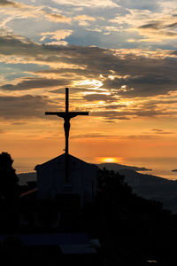 Crucifix on church against sky during sunset