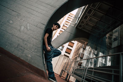 Low angle portrait of young man standing by wall