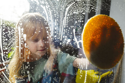 Redhead girl cleaning glass of window