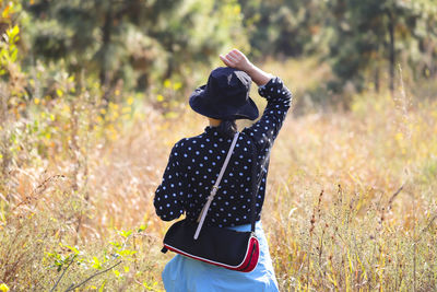 Rear view of woman photographing on field