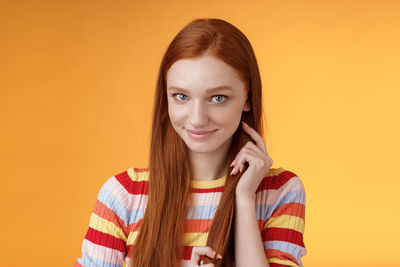 Portrait of smiling woman against orange background
