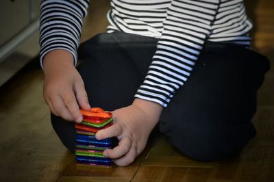 Midsection of boy playing with toys on floor