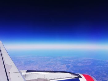 Aerial view of aircraft wing against blue sky