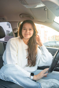 Portrait of young woman sitting in car