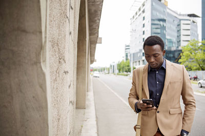 Businessman using smart phone on city street