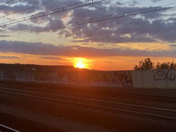 Railroad tracks against sky during sunset