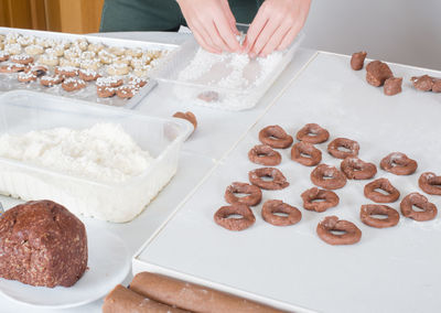 Midsection of person preparing christmas cookies on table