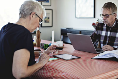 Senior couple using technologies while sitting at dining table