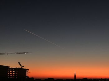 Low angle view of silhouette vapor trail against sky during sunset