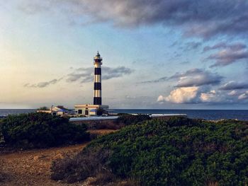 Lighthouse by sea against sky