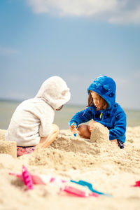 Rear view of children on beach against sky