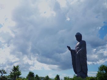 Man standing by statue against sky