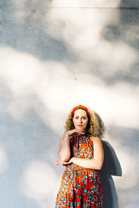 Portrait of young woman standing against wall