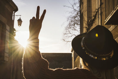 Woman wearing hat against sun at sunset