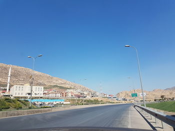 Street by road against clear blue sky