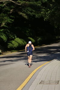 Rear view of man running while wearing swim suit on road